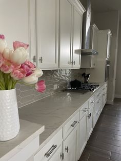 a vase filled with pink and white tulips on top of a kitchen counter