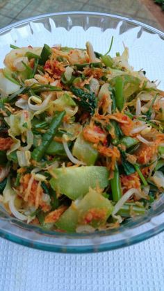 a glass bowl filled with vegetables on top of a table