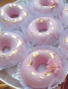 there are pink donuts with gold leaf decorations on the top and bottom, sitting on a plate