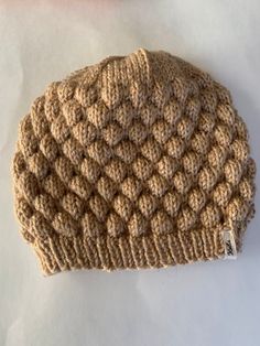 a crocheted hat sitting on top of a white table next to a pink object