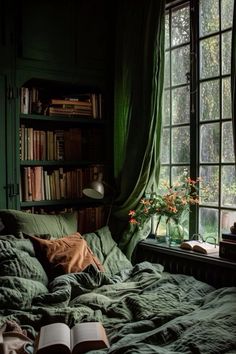 a bed with green sheets and pillows in front of a book shelf filled with books