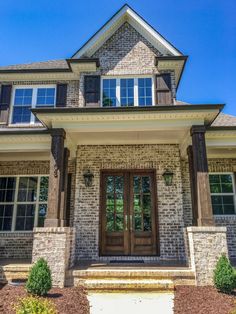 the front entrance to a house with two large windows and brick pillars on each side