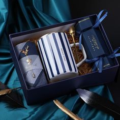 a blue box with white and black striped items in it on a satin table cloth