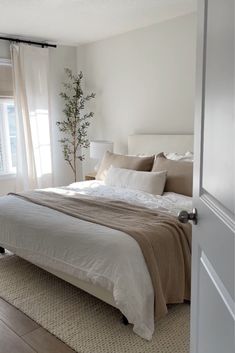 a bedroom with white walls and beige bedding