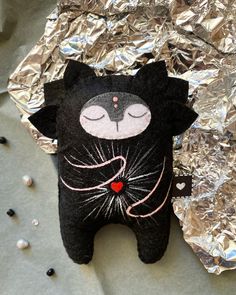 a black cat stuffed animal laying on top of tin foil