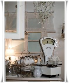 an old fashioned coffee maker and other items on a counter in a room with white walls