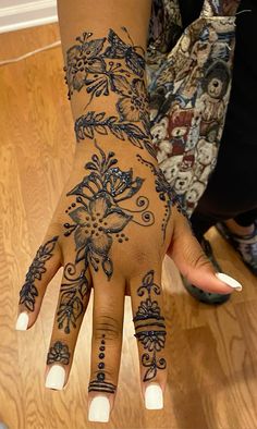 a woman's hand with hennap and flowers on her left arm, showing the