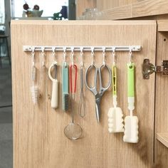 an organized kitchen drawer with utensils and spoons hanging from the handle bar