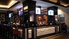 a bar with several stools in front of it and pictures on the wall behind it