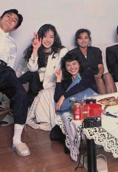 a group of people sitting on top of a couch next to each other in front of a table