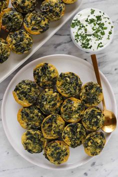 two white plates filled with mini spinach bites next to a bowl of yogurt