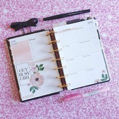 an open planner book sitting on top of a pink table