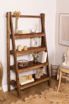 a wooden ladder shelf with books and candles on it in a living room next to a wicker chair