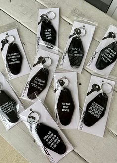 six black and white key tags with words on them sitting on top of a table