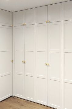 an empty room with white cabinets and wood floors