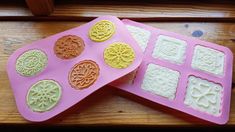 two pink trays filled with different types of cookies on top of a wooden table