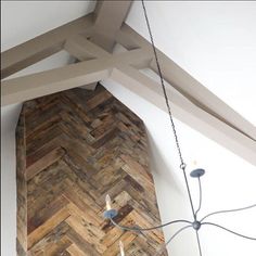 a wooden wall hanging from the ceiling in a room with white walls and wood beams