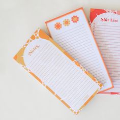 three notepads sitting on top of each other next to an orange and white paper