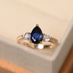 an engagement ring with a blue sapphire and three white diamonds on the side in a box