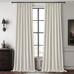 a white curtain hangs in front of a window with a black lamp on the side