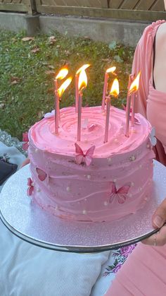 a woman holding a cake with lit candles on it