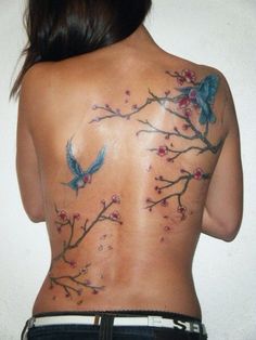 the back of a woman's body with birds and flowers tattooed on her back