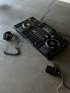 there is a dj mixer and headphones on the floor next to eachother