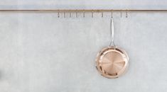 a copper pan hanging on a wall next to a coat rack