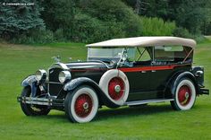 an antique car is parked in the grass