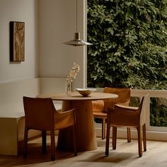 a table and chairs in front of a window with plants on the wall behind it