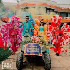 a group of people standing next to each other in front of a vehicle with colorful decorations on it