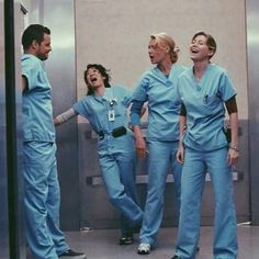 four doctors laughing and standing in front of an elevator with their arms around each other