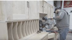 a man using a circular saw to cut plywood planks with a machine in the background