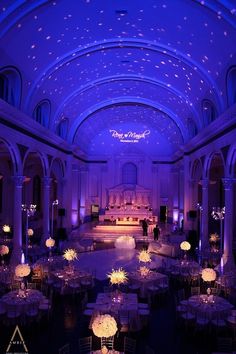 an indoor wedding venue with purple lighting and chandeliers on the ceiling is lit up