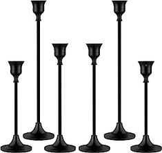 four black candlesticks are lined up in the same row on a white background