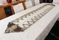 the table is covered with white linens and decorative beadwork, which has been placed on top of it