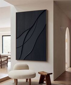 an abstract painting hangs on the wall above a chair and footstool in a living room