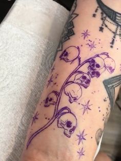 a woman's arm with skulls and stars on it, while she is wearing a purple tattoo