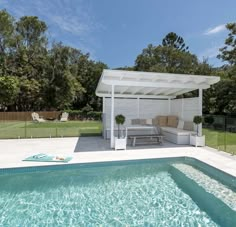 a pool with a white pergola and lounge chairs next to it in the middle of a yard