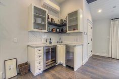 an empty kitchen with white cabinets and wood flooring is pictured in this image, there are shelves above the stove