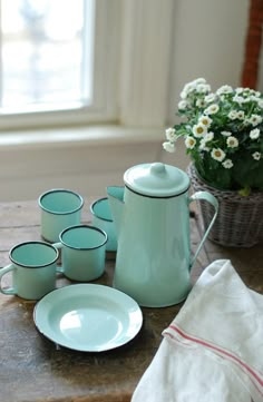 a table topped with blue dishes and cups next to a vase filled with white flowers