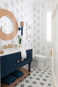 a white and blue bathroom with an oval mirror on the wall above the vanity, toilet and sink