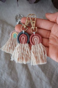 a person holding two pairs of tasseled earrings in their hand, one with a pair of scissors on it