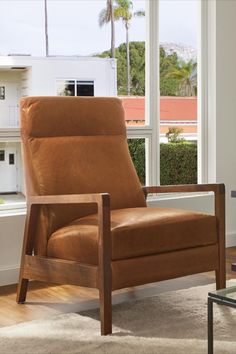 a brown leather chair sitting in front of a window