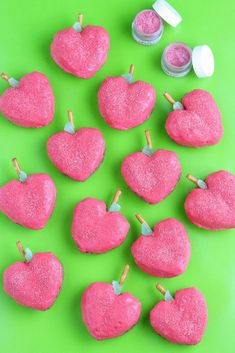 pink heart shaped candies with toothpicks on green surface next to small jars