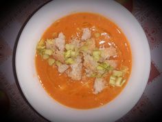 a white bowl filled with soup and garnishes on top of a table