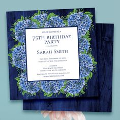 a blue and white birthday party card with flowers on the front, surrounded by greenery