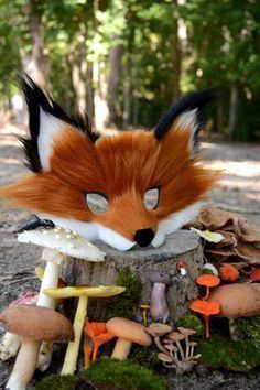 a fake fox head sitting on top of a tree stump next to mushrooms and mushrooms