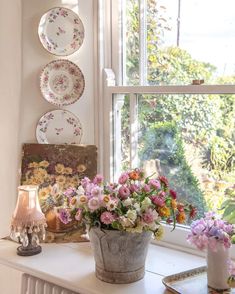 a window sill with flowers and plates on it