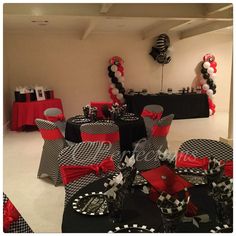 a room filled with black and white tables covered in red and black tablecloths